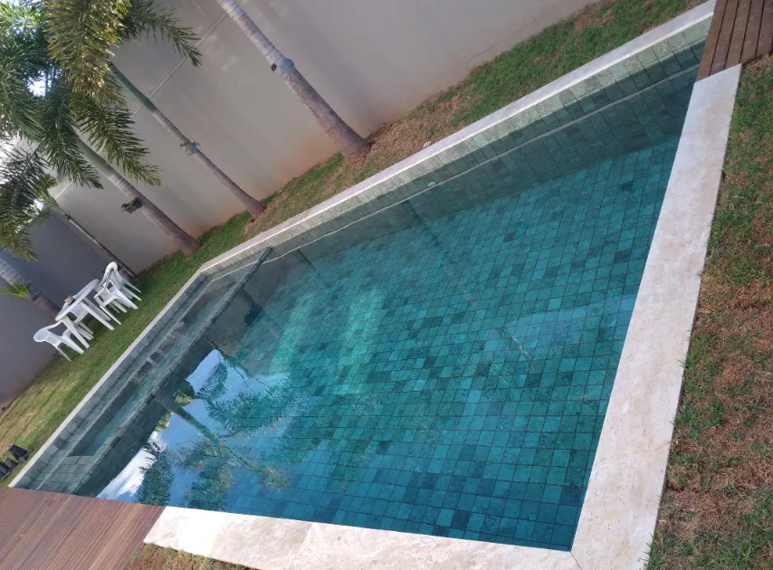 Piscina residencial revestida em tons de verde e azul